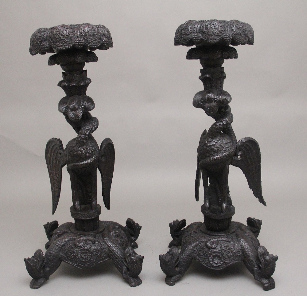 A pair of 19th-century Anglo-Indian carved hardwood torcheres featuring detailed cobra and mythical bird motifs topped with lotus platforms. View II
