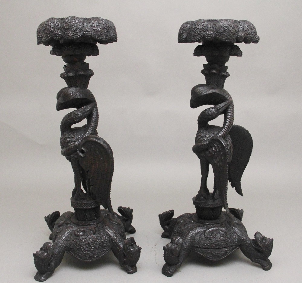 A pair of 19th-century Anglo-Indian carved hardwood torcheres featuring detailed cobra and mythical bird motifs topped with lotus platforms. View III