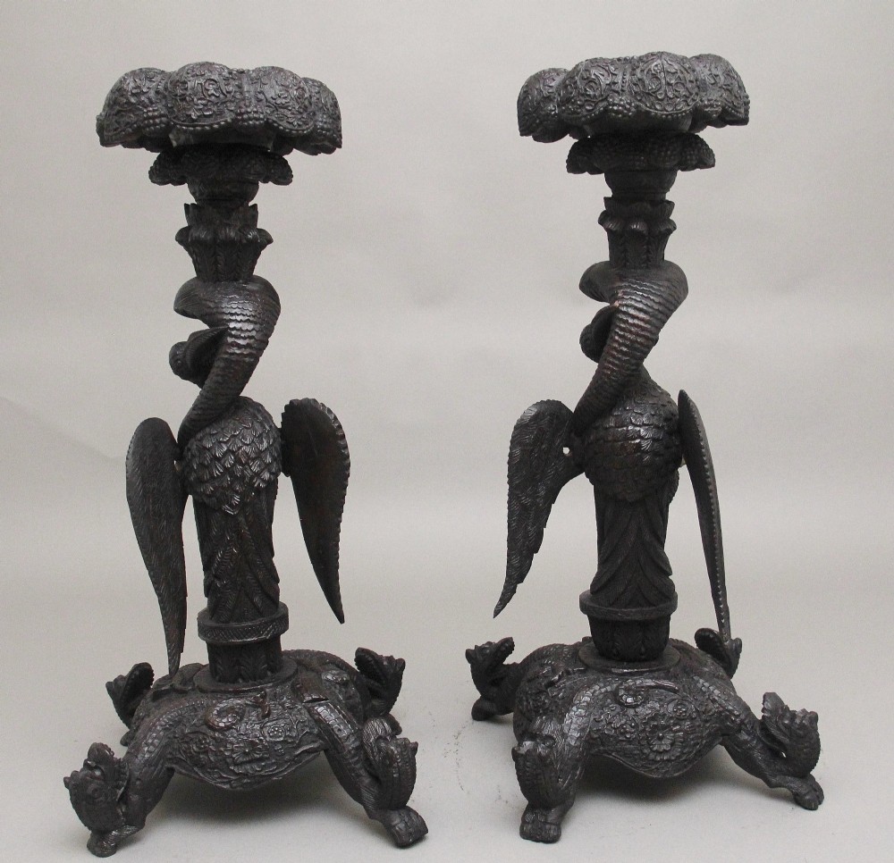 A pair of 19th-century Anglo-Indian carved hardwood torcheres featuring detailed cobra and mythical bird motifs topped with lotus platforms. View IV