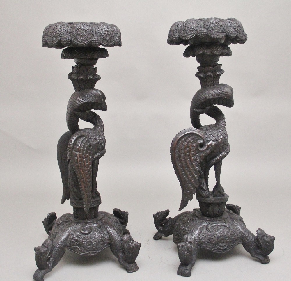 A pair of 19th-century Anglo-Indian carved hardwood torcheres featuring detailed cobra and mythical bird motifs topped with lotus platforms. View V