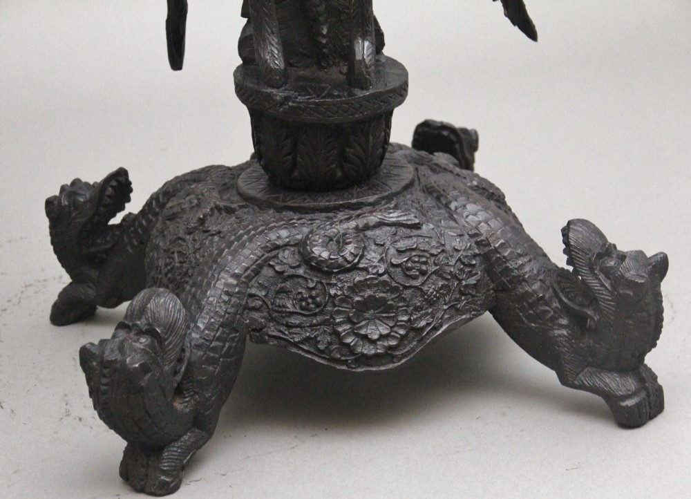 A pair of 19th-century Anglo-Indian carved hardwood torcheres featuring detailed cobra and mythical bird motifs topped with lotus platforms. View VII
