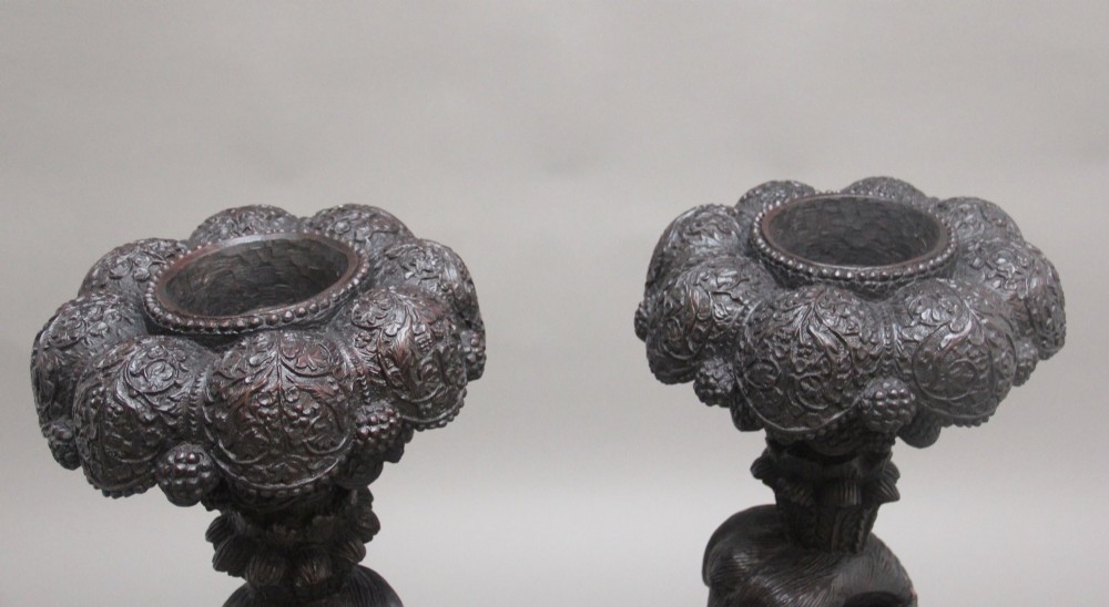 A pair of 19th-century Anglo-Indian carved hardwood torcheres featuring detailed cobra and mythical bird motifs topped with lotus platforms. View IX