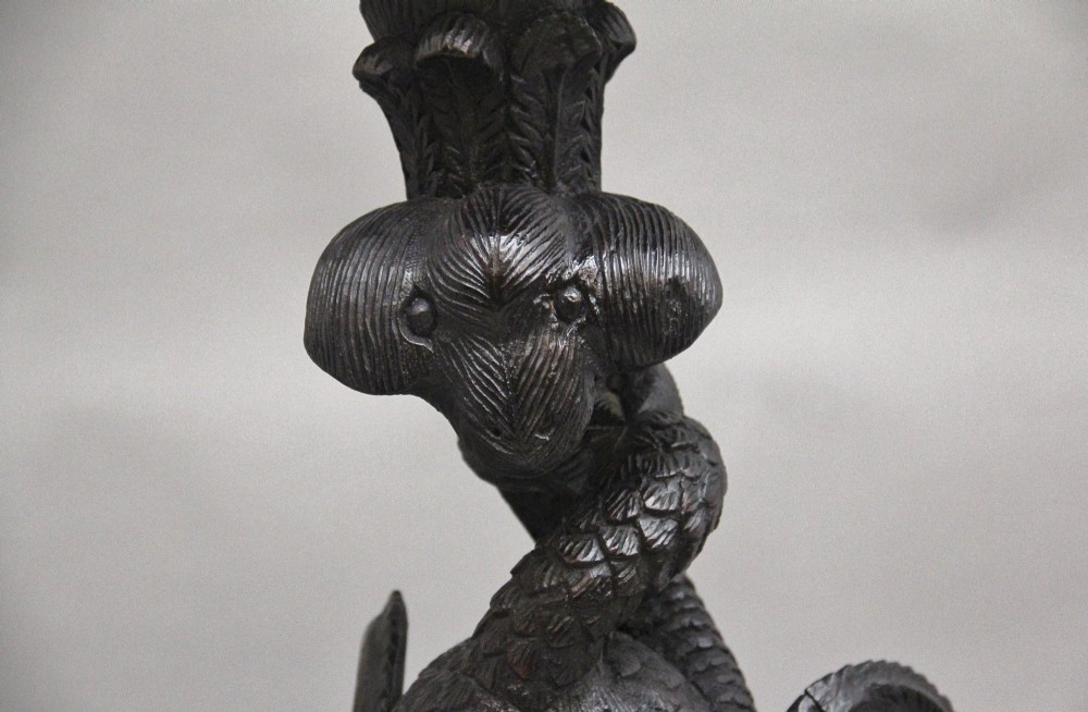 A pair of 19th-century Anglo-Indian carved hardwood torcheres featuring detailed cobra and mythical bird motifs topped with lotus platforms. View X