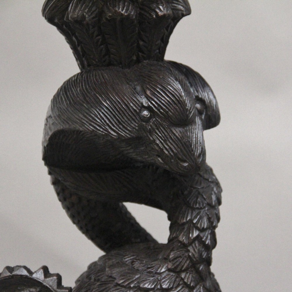 A pair of 19th-century Anglo-Indian carved hardwood torcheres featuring detailed cobra and mythical bird motifs topped with lotus platforms. View XII