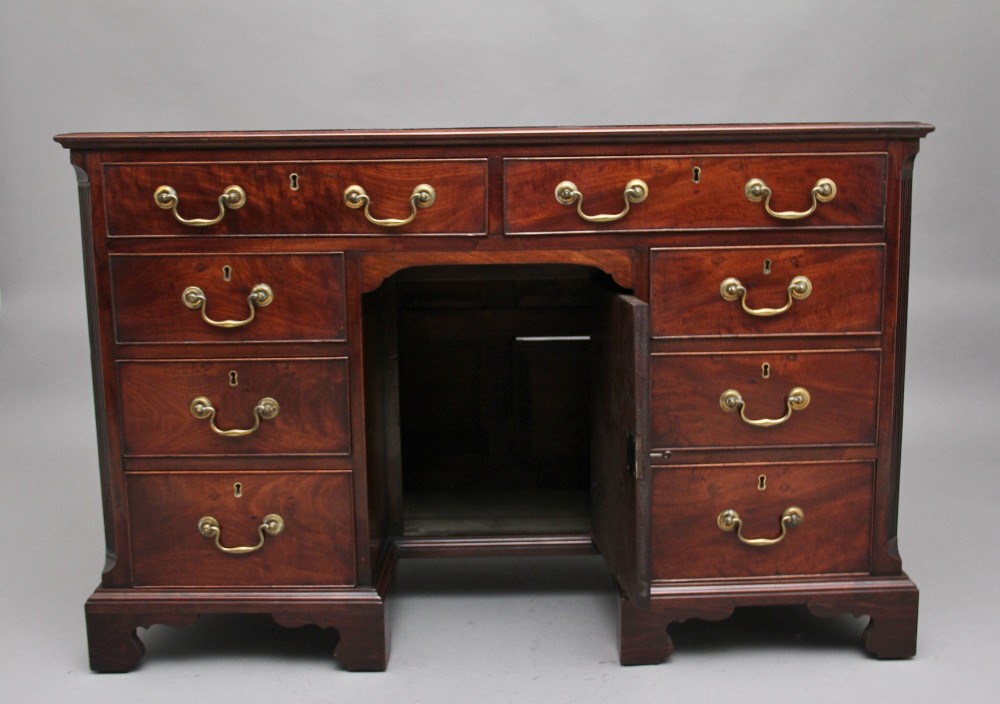 An 18th-century mahogany kneehole desk featuring a central recessed cupboard, multiple drawers with brass swan-neck handles, and bracket feet. View II