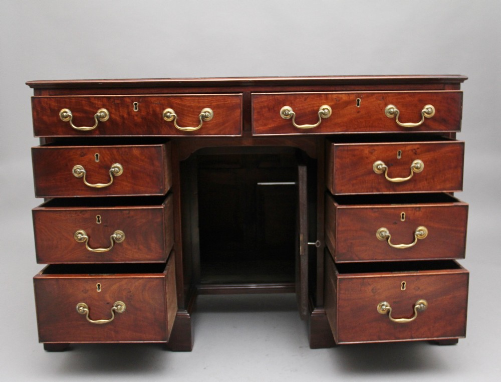 An 18th-century mahogany kneehole desk featuring a central recessed cupboard, multiple drawers with brass swan-neck handles, and bracket feet. View III