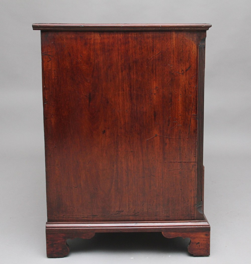 An 18th-century mahogany kneehole desk featuring a central recessed cupboard, multiple drawers with brass swan-neck handles, and bracket feet. View VII