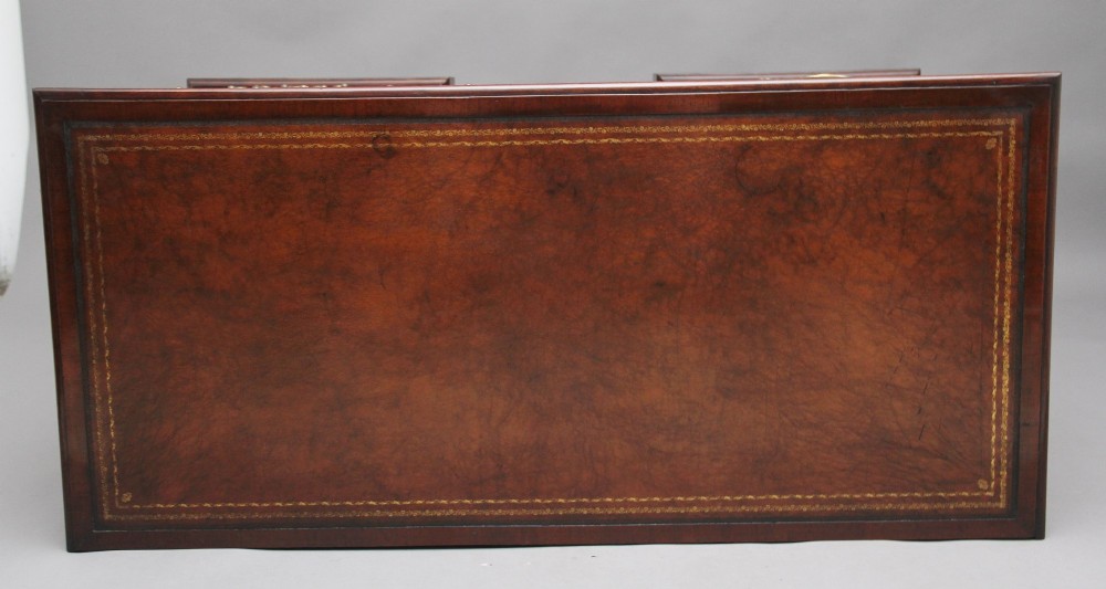 An 18th-century mahogany kneehole desk featuring a central recessed cupboard, multiple drawers with brass swan-neck handles, and bracket feet. View X