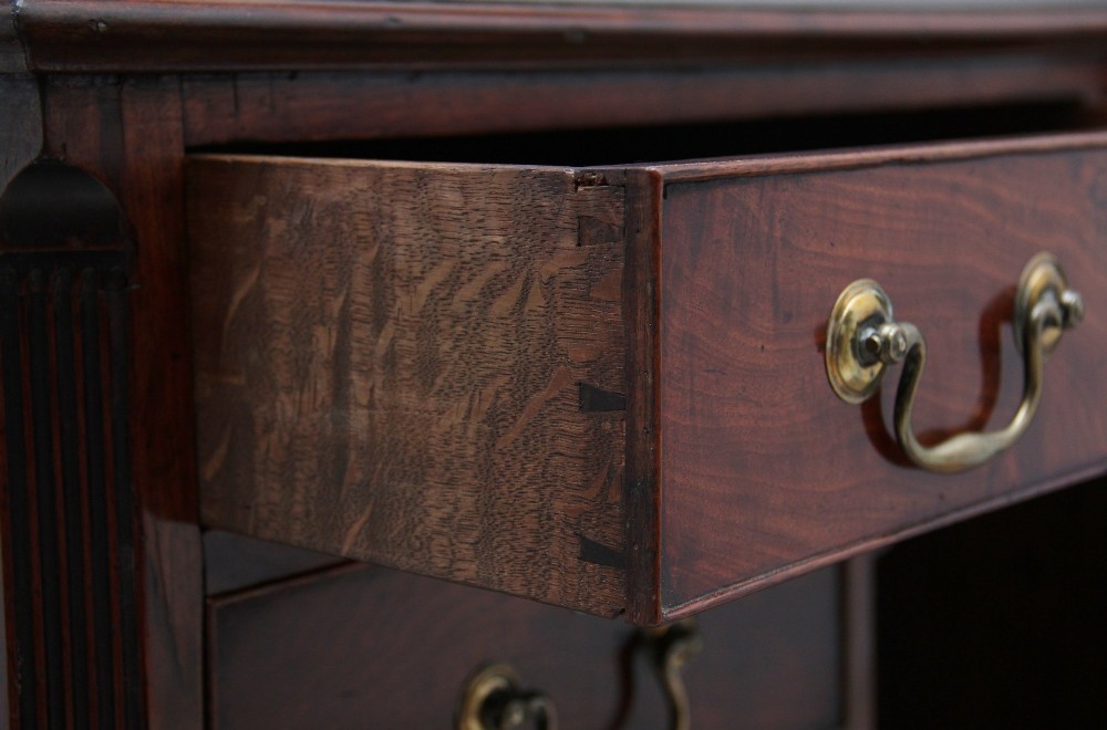 An 18th-century mahogany kneehole desk featuring a central recessed cupboard, multiple drawers with brass swan-neck handles, and bracket feet. View XII
