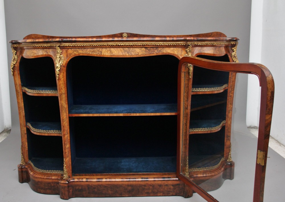 A 19th-century burr walnut credenza featuring a central glazed door, flanking curved open display shelves, and gilt ormolu mounts. View II