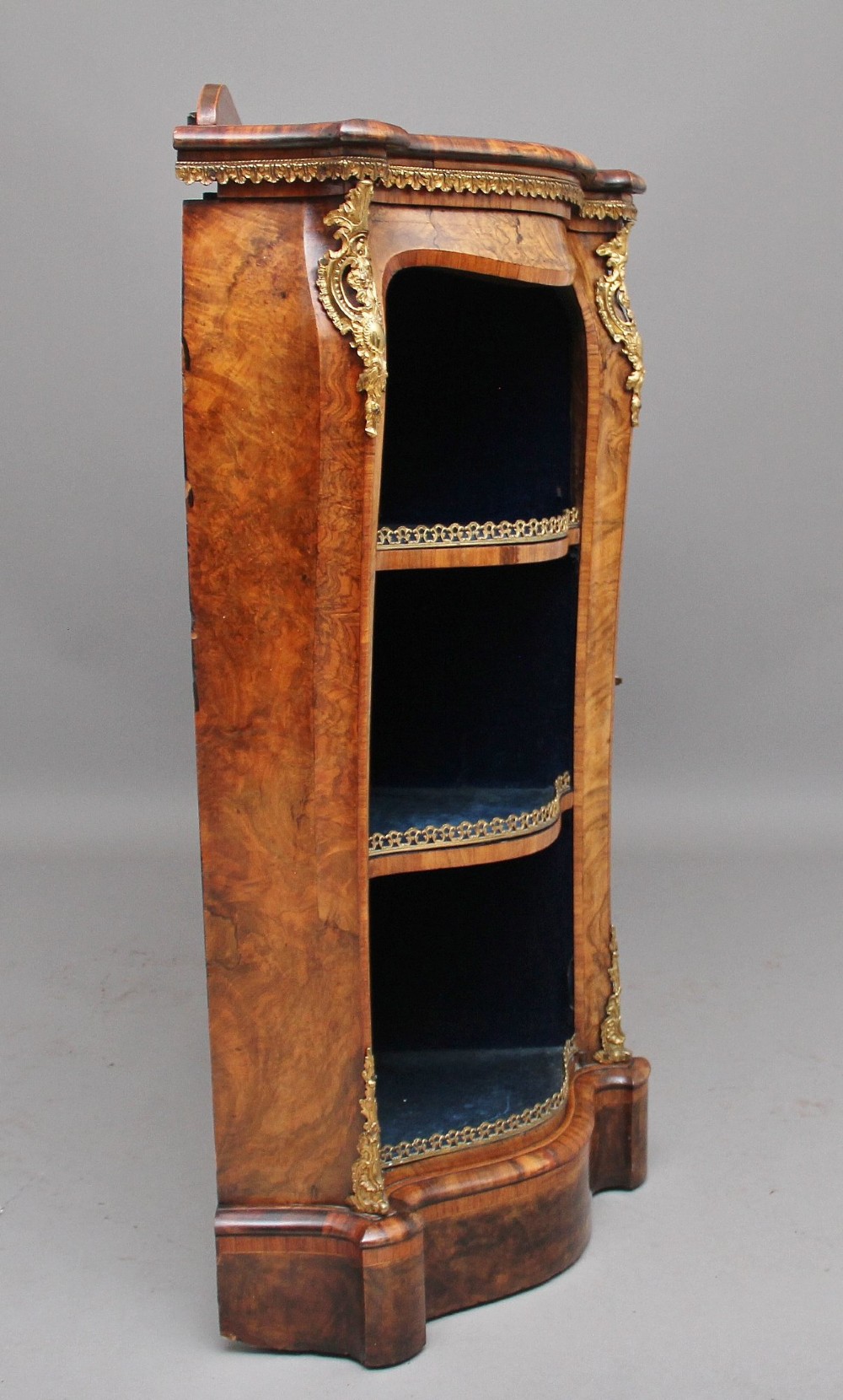 A 19th-century burr walnut credenza featuring a central glazed door, flanking curved open display shelves, and gilt ormolu mounts. View III