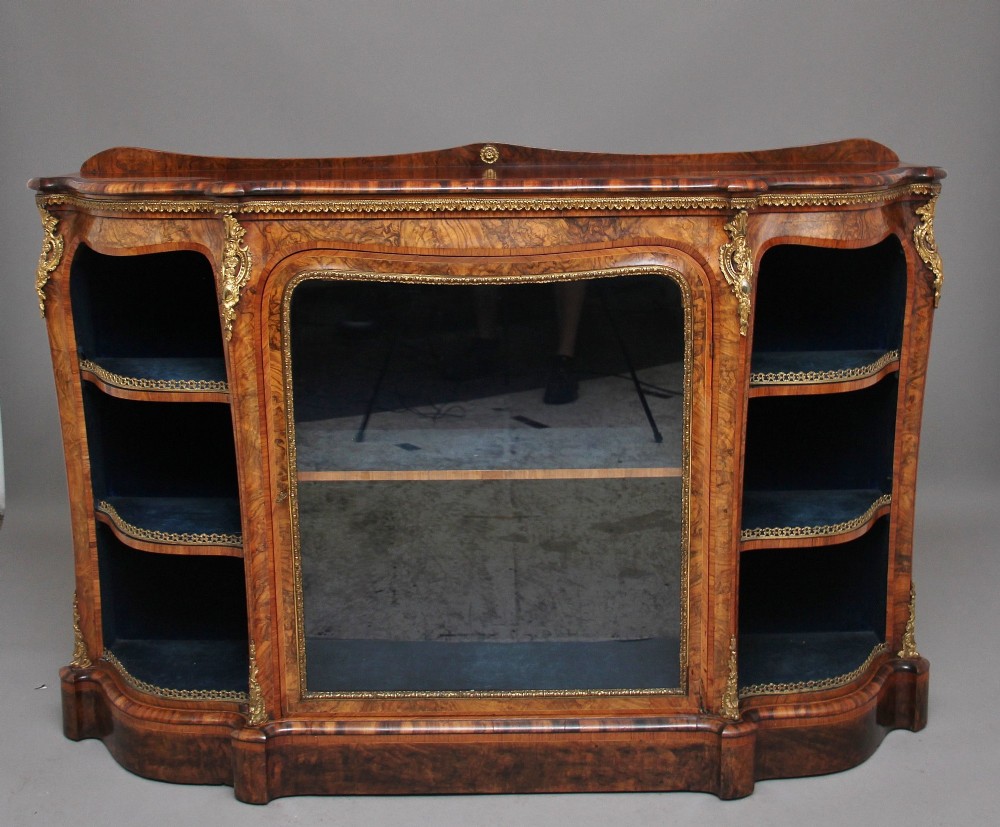 A 19th-century burr walnut credenza featuring a central glazed door, flanking curved open display shelves, and gilt ormolu mounts. View IX