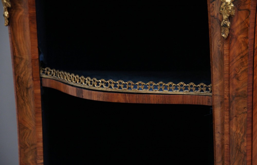 A 19th-century burr walnut credenza featuring a central glazed door, flanking curved open display shelves, and gilt ormolu mounts. View XI