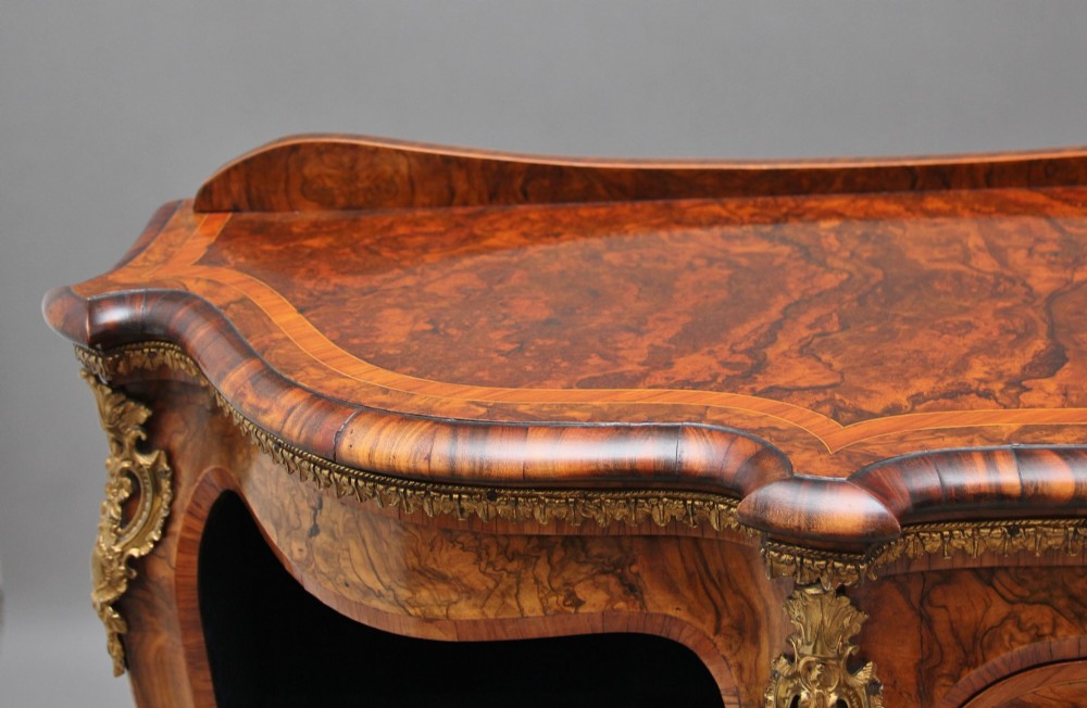 A 19th-century burr walnut credenza featuring a central glazed door, flanking curved open display shelves, and gilt ormolu mounts. View XIV