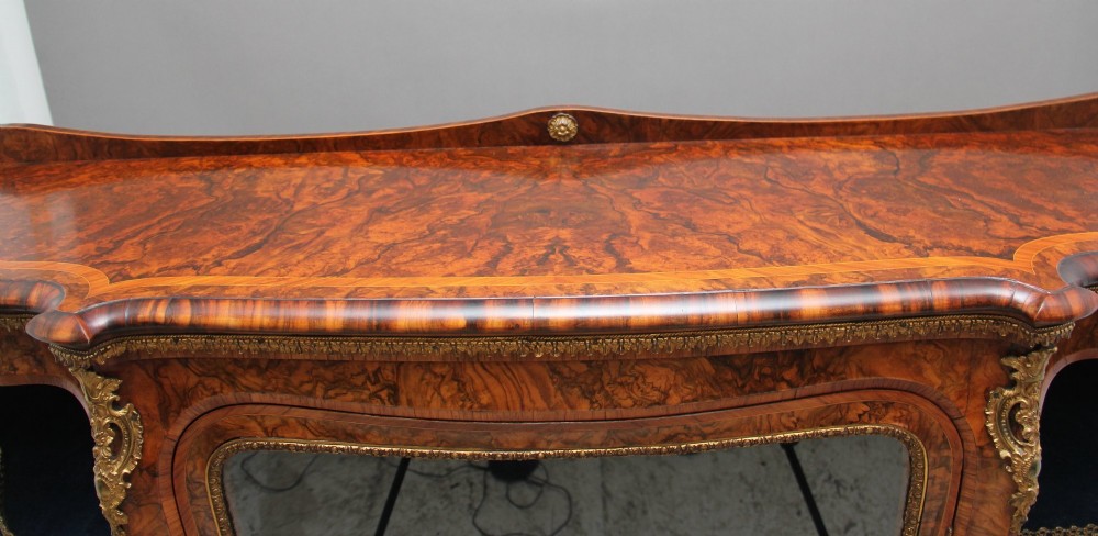 A 19th-century burr walnut credenza featuring a central glazed door, flanking curved open display shelves, and gilt ormolu mounts. View XV