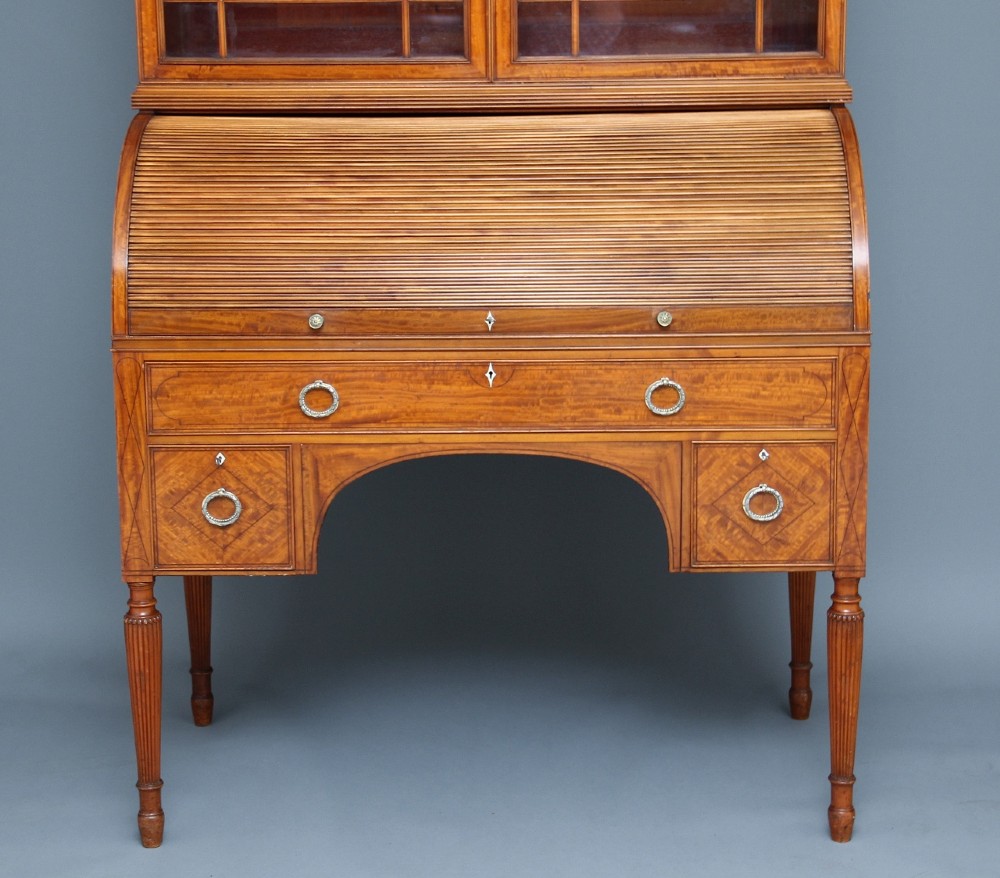 A 19th-century satinwood bureau bookcase featuring a two-door glazed upper section, a cylinder roll-top writing section, lower drawers with ring handles, and turned legs. View VIII