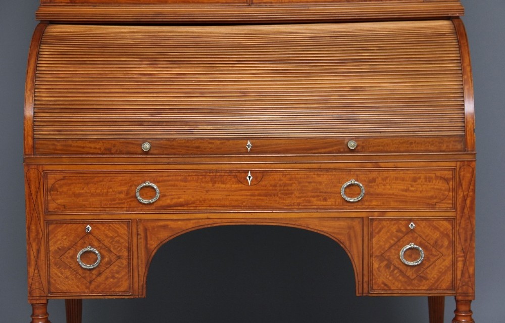 A 19th-century satinwood bureau bookcase featuring a two-door glazed upper section, a cylinder roll-top writing section, lower drawers with ring handles, and turned legs. View IX