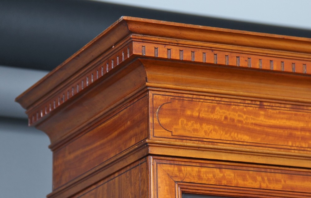 A 19th-century satinwood bureau bookcase featuring a two-door glazed upper section, a cylinder roll-top writing section, lower drawers with ring handles, and turned legs. View X