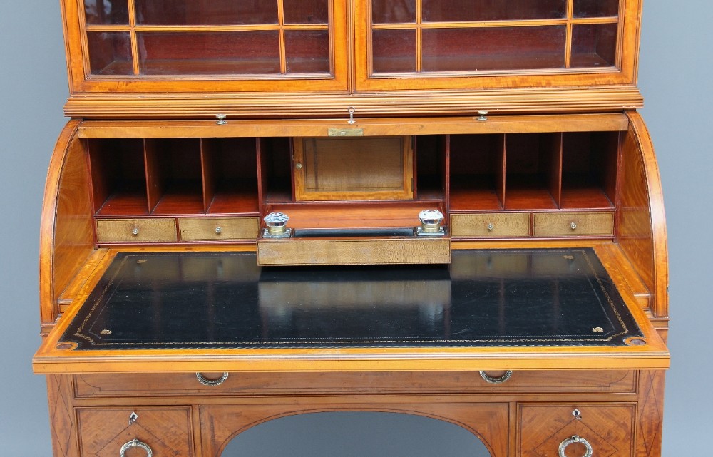 A 19th-century satinwood bureau bookcase featuring a two-door glazed upper section, a cylinder roll-top writing section, lower drawers with ring handles, and turned legs. View XIV