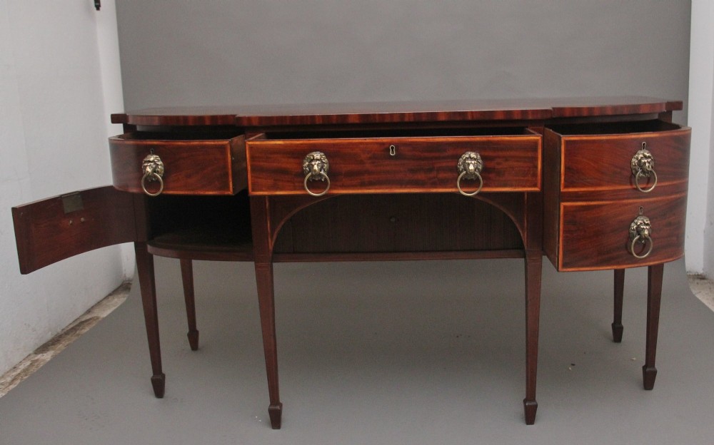 A nineteenth-century mahogany bowfront sideboard featuring inlaid crossbanding, multiple drawers with brass lion-mask ring handles, and tapered square legs. View II
