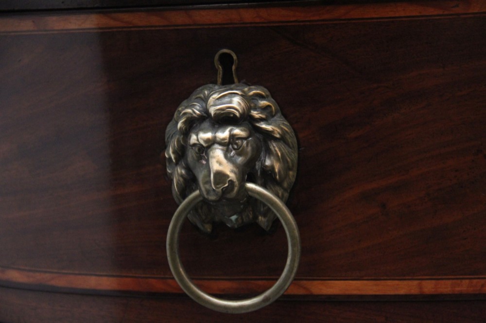 A nineteenth-century mahogany bowfront sideboard featuring inlaid crossbanding, multiple drawers with brass lion-mask ring handles, and tapered square legs. View VIII