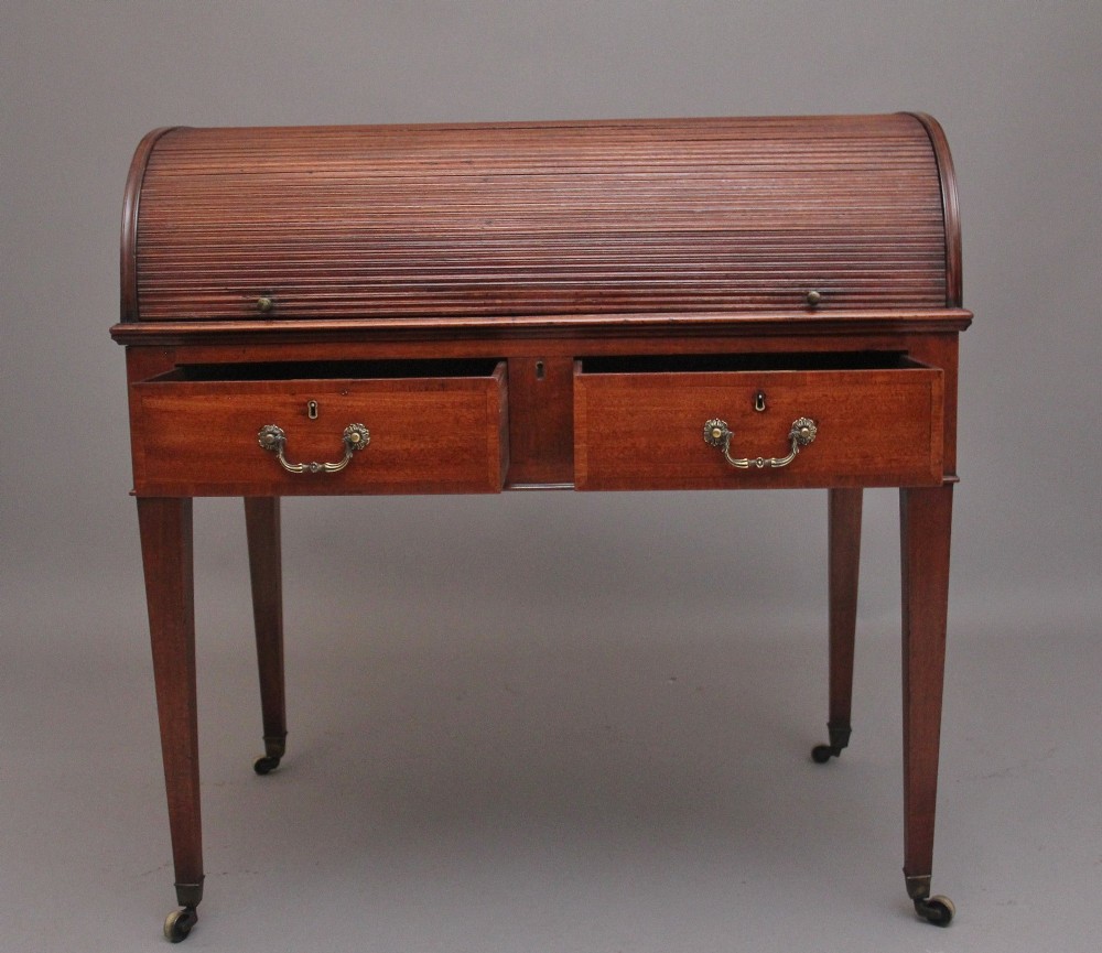 An early nineteenth-century mahogany tambour desk featuring a slatted roll-top cover, two drawers with brass handles, and square tapered legs on castors. View II