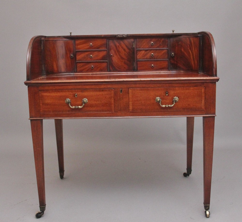 An early nineteenth-century mahogany tambour desk featuring a slatted roll-top cover, two drawers with brass handles, and square tapered legs on castors. View III