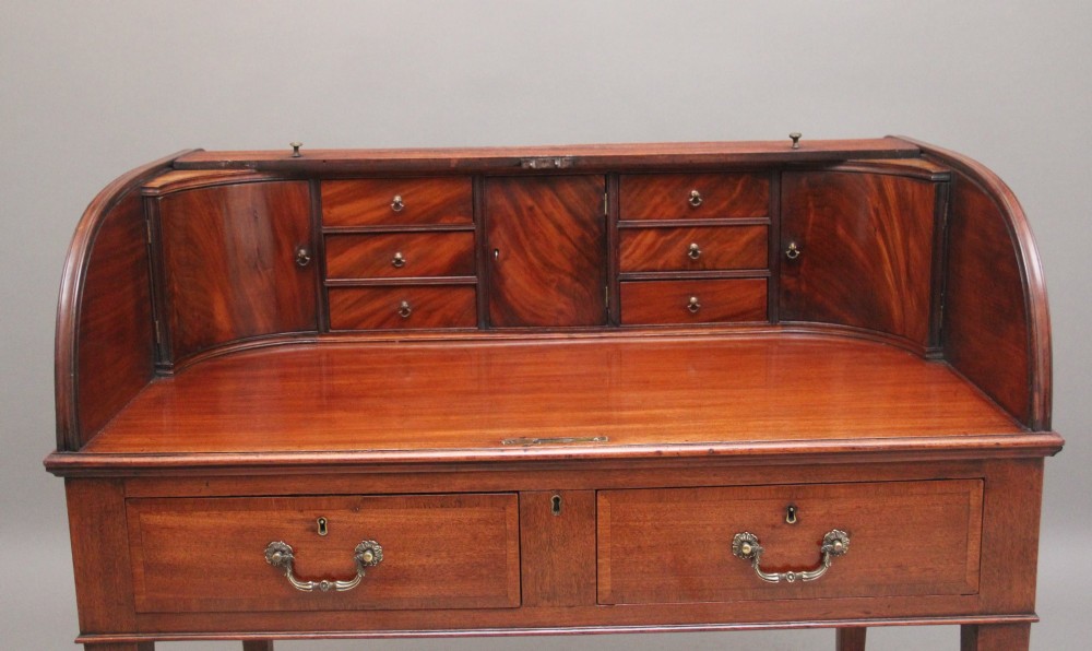 An early nineteenth-century mahogany tambour desk featuring a slatted roll-top cover, two drawers with brass handles, and square tapered legs on castors. View IV