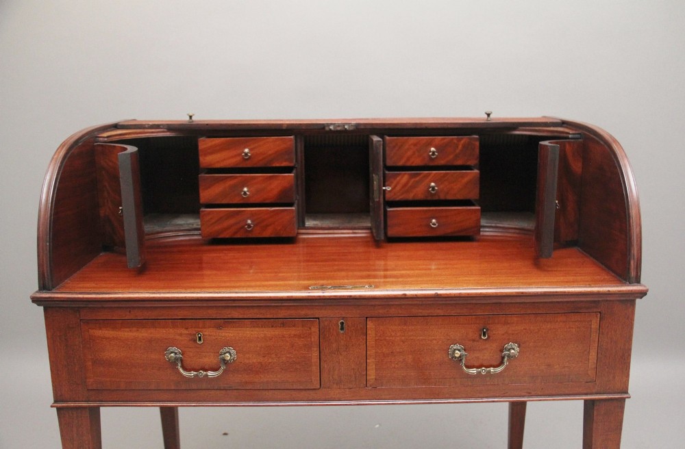 An early nineteenth-century mahogany tambour desk featuring a slatted roll-top cover, two drawers with brass handles, and square tapered legs on castors. View V