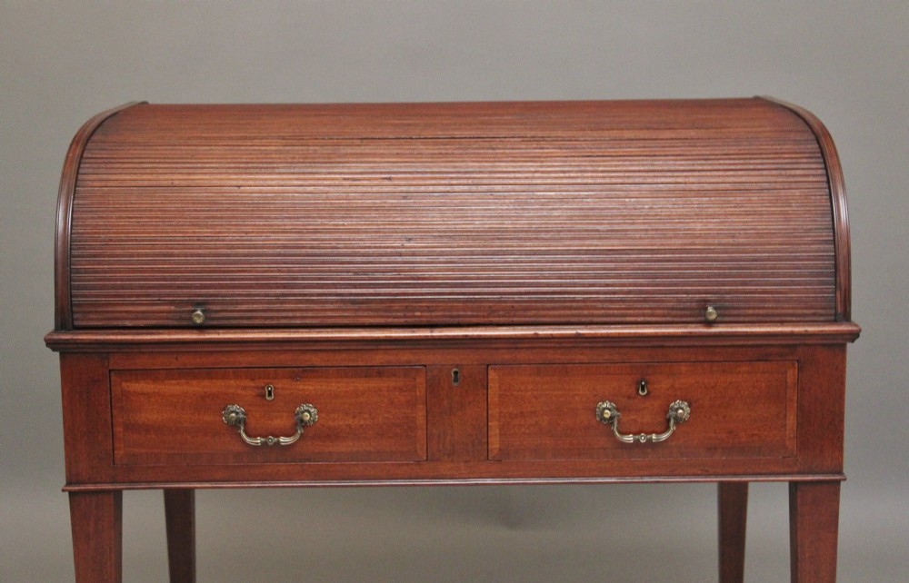 An early nineteenth-century mahogany tambour desk featuring a slatted roll-top cover, two drawers with brass handles, and square tapered legs on castors. View VI