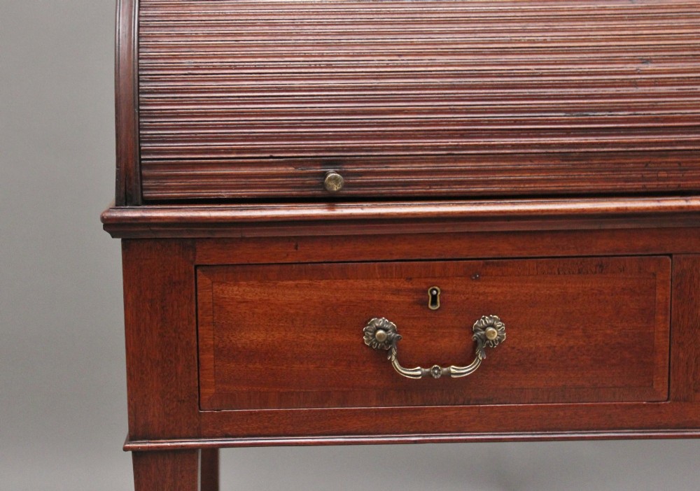 An early nineteenth-century mahogany tambour desk featuring a slatted roll-top cover, two drawers with brass handles, and square tapered legs on castors. View VII