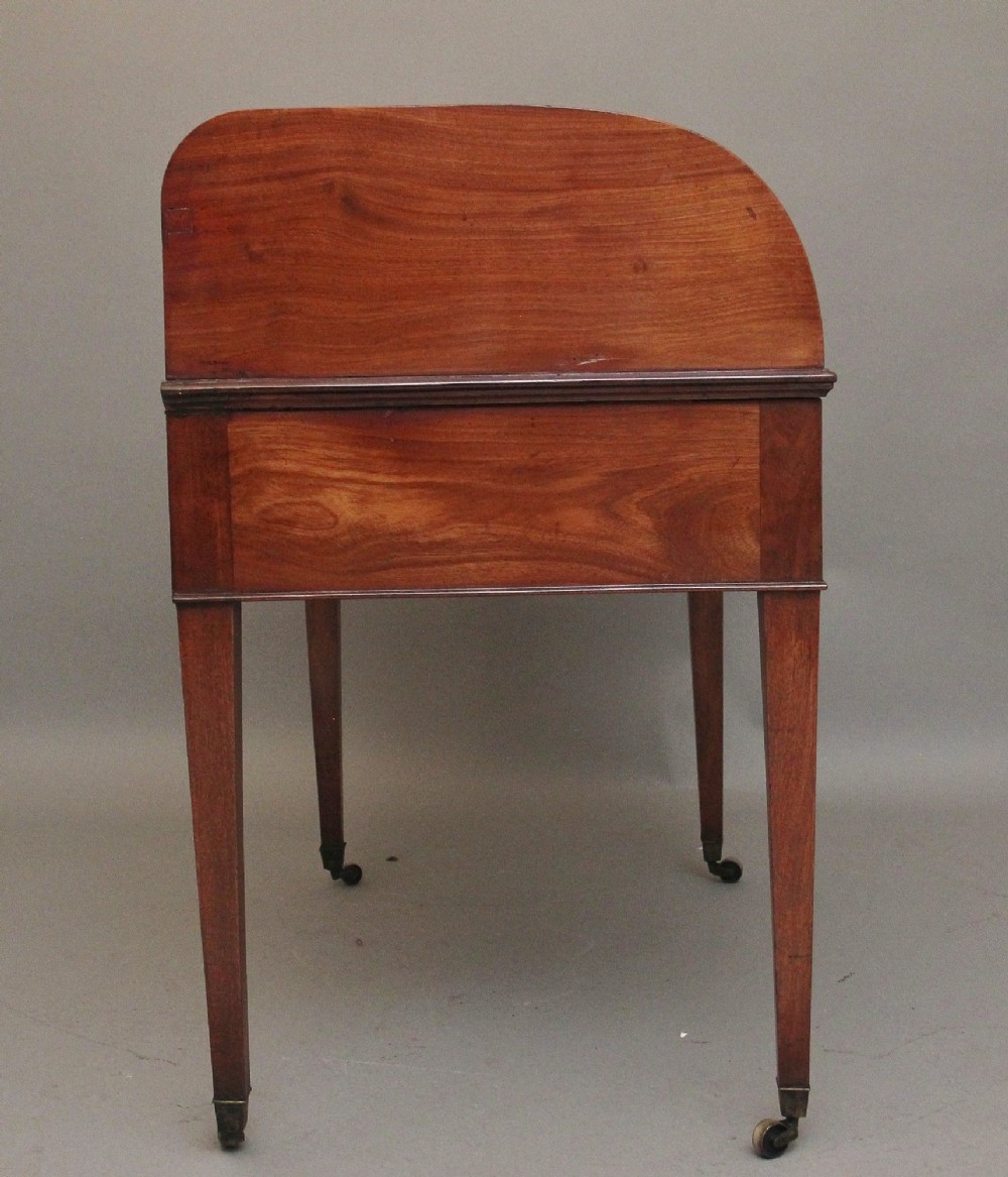 An early nineteenth-century mahogany tambour desk featuring a slatted roll-top cover, two drawers with brass handles, and square tapered legs on castors. View VIII