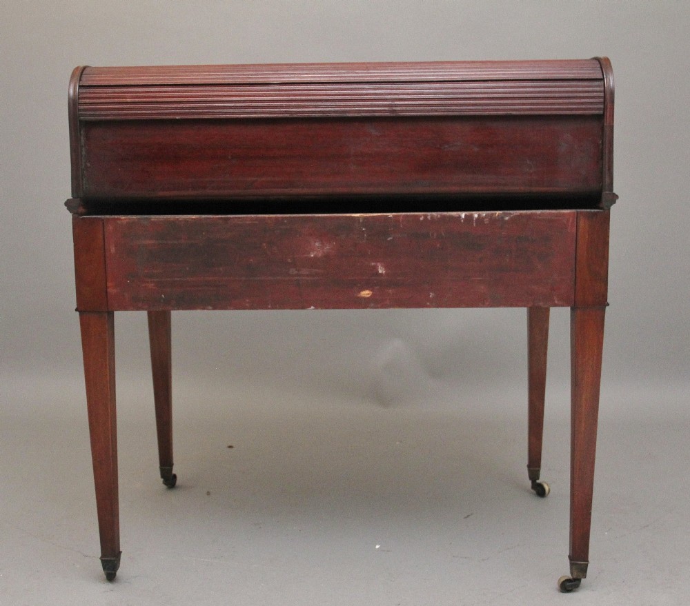 An early nineteenth-century mahogany tambour desk featuring a slatted roll-top cover, two drawers with brass handles, and square tapered legs on castors. View IX