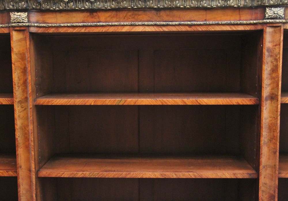 A nineteenth-century low open bookcase crafted from warm walnut wood featuring three sections with adjustable shelving and decorative gilt-bronze ormolu mounts along the borders. View II