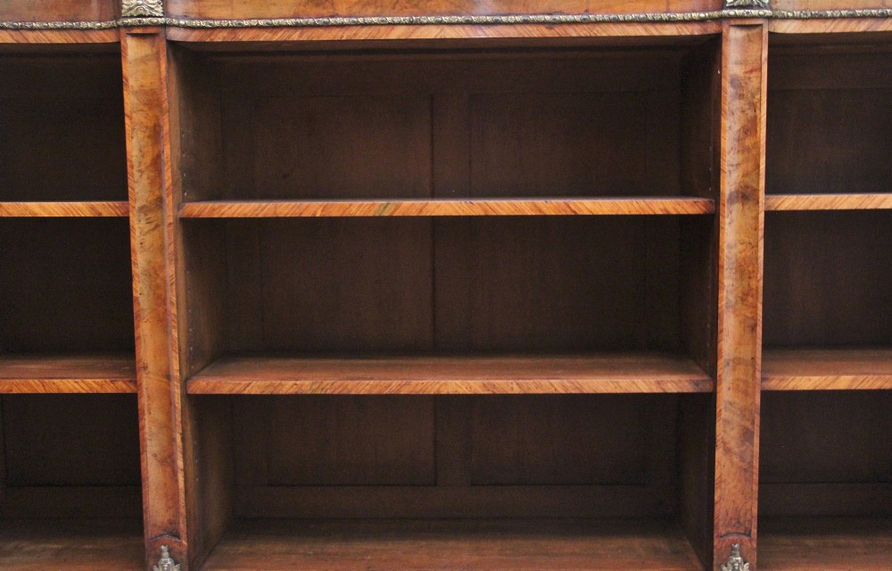 A nineteenth-century low open bookcase crafted from warm walnut wood featuring three sections with adjustable shelving and decorative gilt-bronze ormolu mounts along the borders. View IV