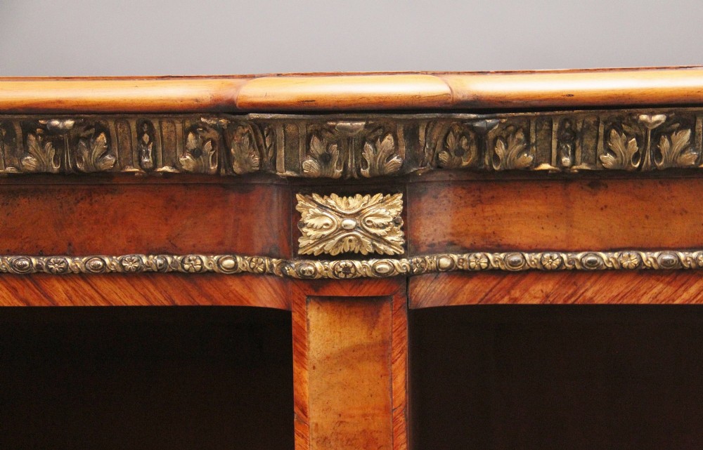 A nineteenth-century low open bookcase crafted from warm walnut wood featuring three sections with adjustable shelving and decorative gilt-bronze ormolu mounts along the borders. View VI