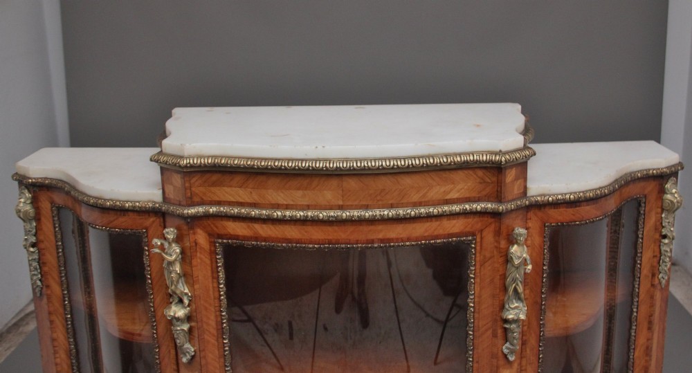 A 19th-century French kingwood credenza featuring a stepped white marble top, three glazed doors, parquetry veneer, and cast gilt-bronze caryatid mounts. View IV