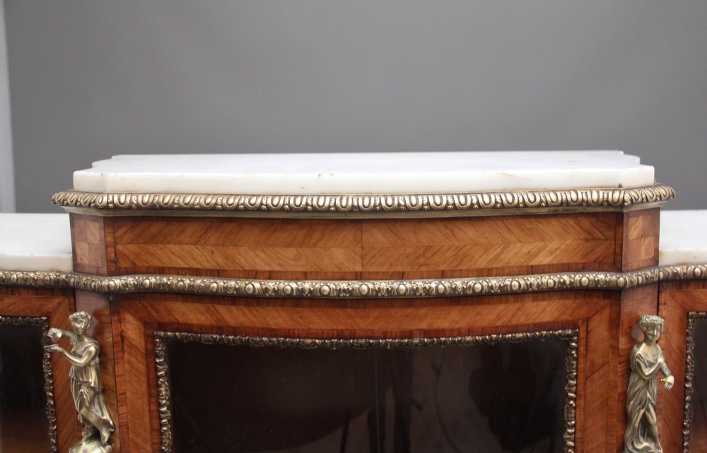 A 19th-century French kingwood credenza featuring a stepped white marble top, three glazed doors, parquetry veneer, and cast gilt-bronze caryatid mounts. View VI