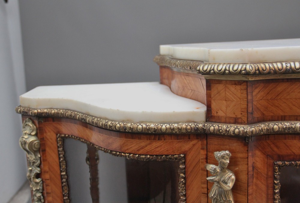 A 19th-century French kingwood credenza featuring a stepped white marble top, three glazed doors, parquetry veneer, and cast gilt-bronze caryatid mounts. View VII