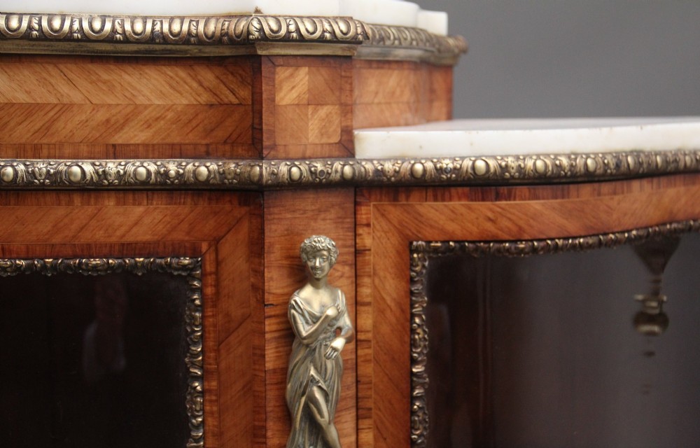 A 19th-century French kingwood credenza featuring a stepped white marble top, three glazed doors, parquetry veneer, and cast gilt-bronze caryatid mounts. View IX