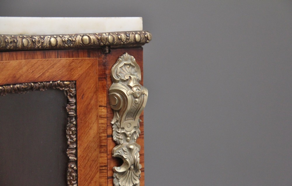 A 19th-century French kingwood credenza featuring a stepped white marble top, three glazed doors, parquetry veneer, and cast gilt-bronze caryatid mounts. View X