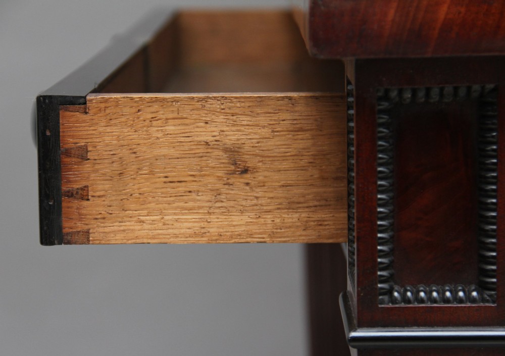 An early nineteenth-century mahogany cabinet on stand featuring flame-veneered panelled double doors above a drawer, supported by turned reeded legs. View XIII