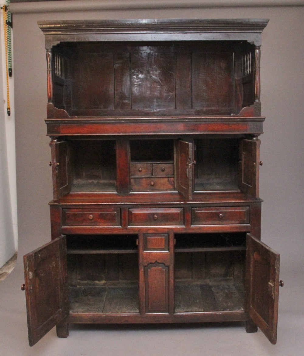 An early eighteenth-century dark Welsh oak tridarn featuring a three-tier design with an open top canopy, middle cupboards with arched panels, and a lower section with drawers and doors. View II