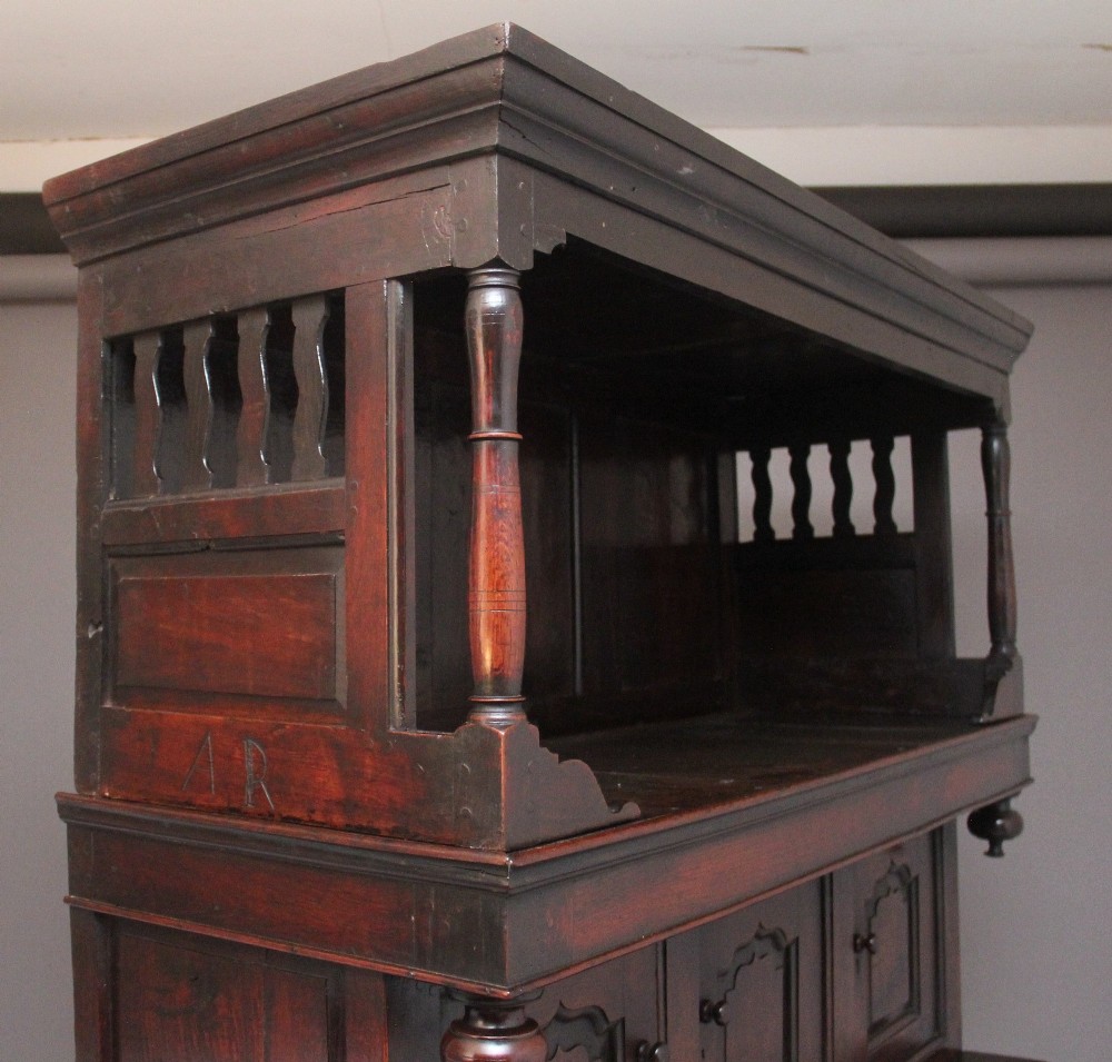 An early eighteenth-century dark Welsh oak tridarn featuring a three-tier design with an open top canopy, middle cupboards with arched panels, and a lower section with drawers and doors. View V