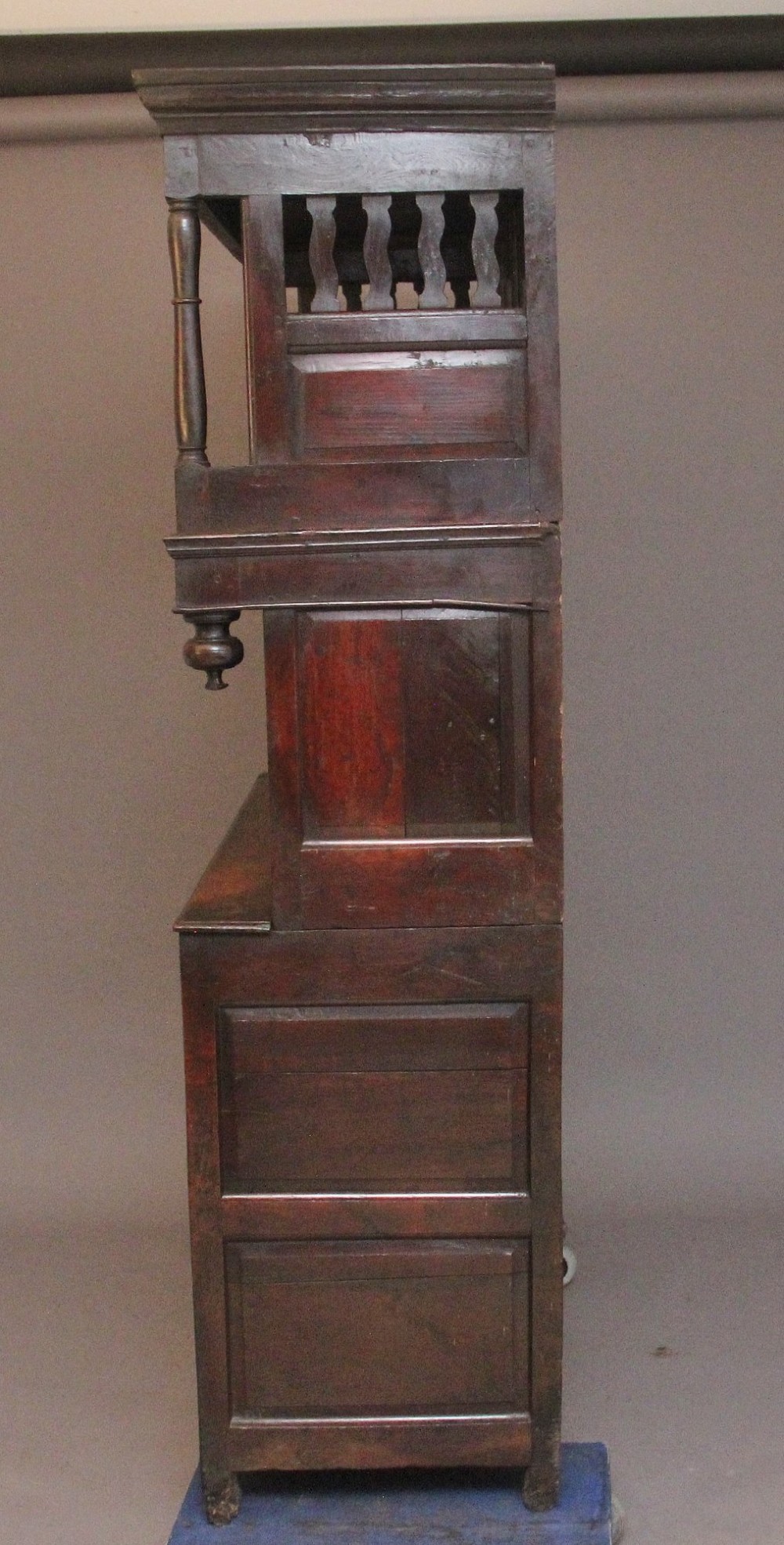 An early eighteenth-century dark Welsh oak tridarn featuring a three-tier design with an open top canopy, middle cupboards with arched panels, and a lower section with drawers and doors. View VIII