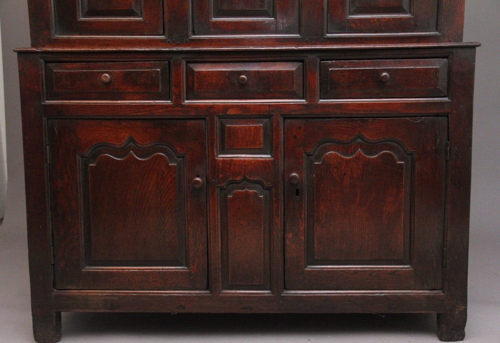 An early eighteenth-century dark Welsh oak tridarn featuring a three-tier design with an open top canopy, middle cupboards with arched panels, and a lower section with drawers and doors. View X