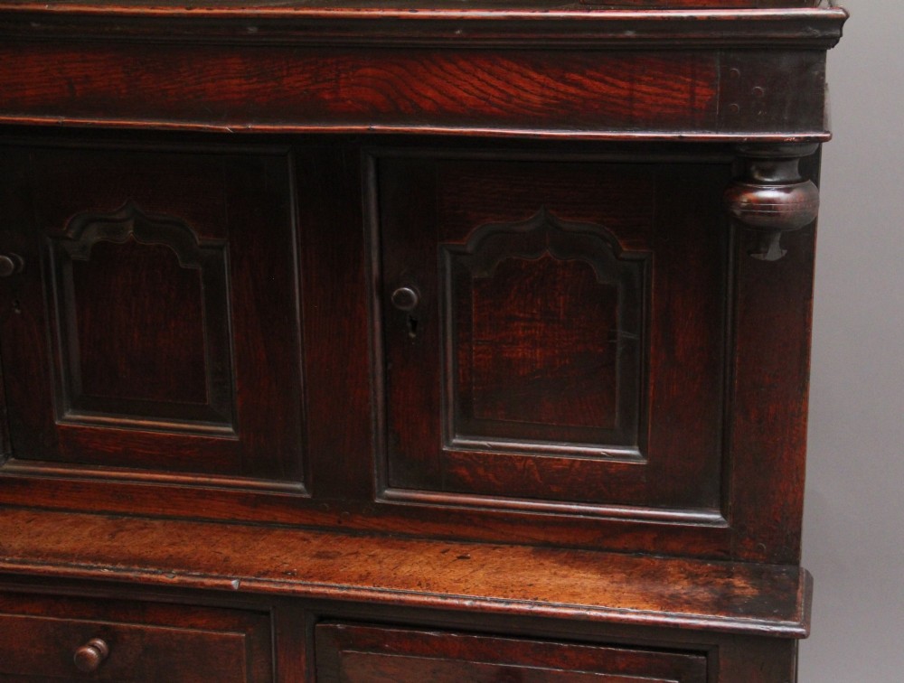 An early eighteenth-century dark Welsh oak tridarn featuring a three-tier design with an open top canopy, middle cupboards with arched panels, and a lower section with drawers and doors. View XIII