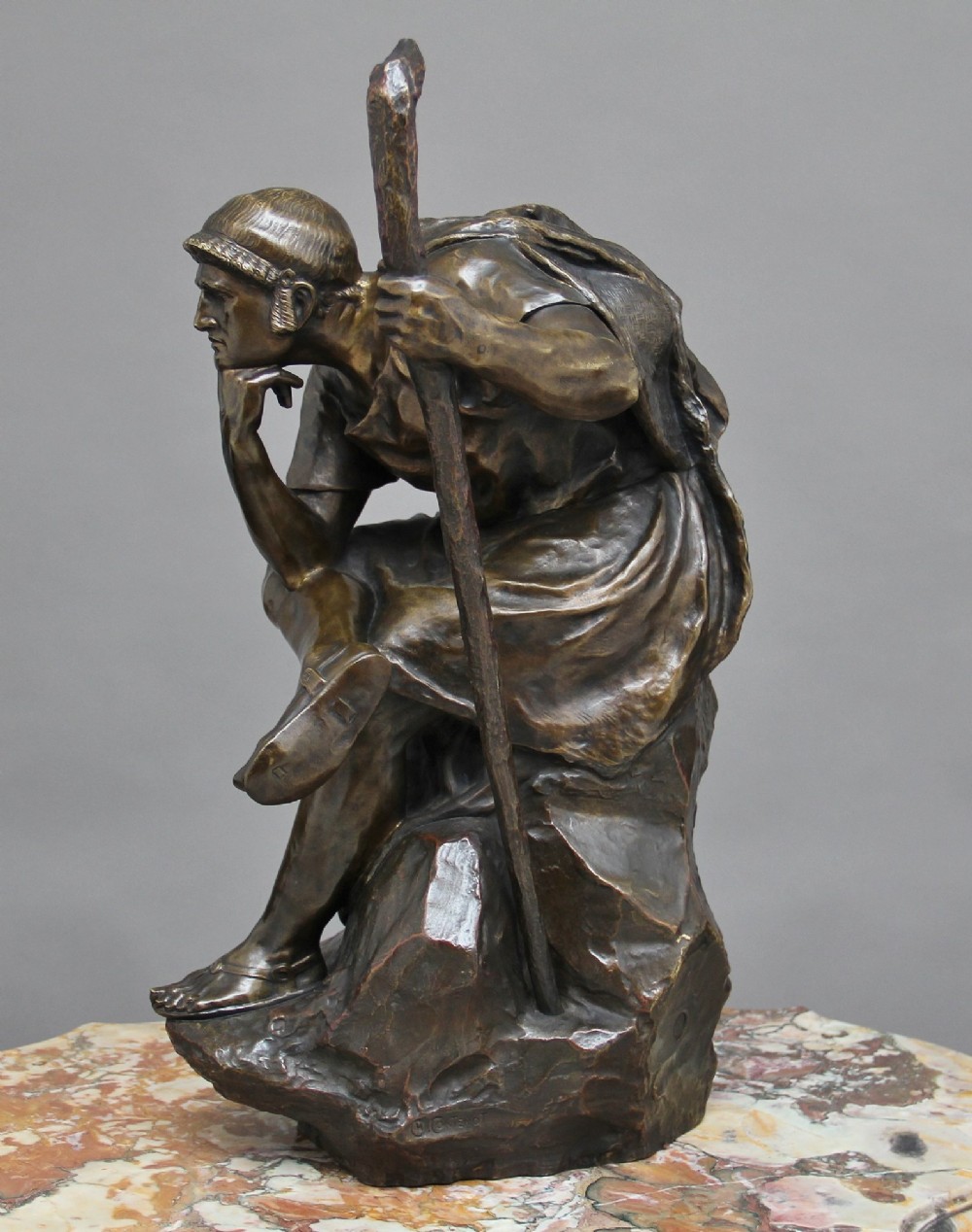 A 19th-century patinated bronze sculpture depicting the mythological figure Oedipus seated on a rock in contemplation while holding a staff. View IV