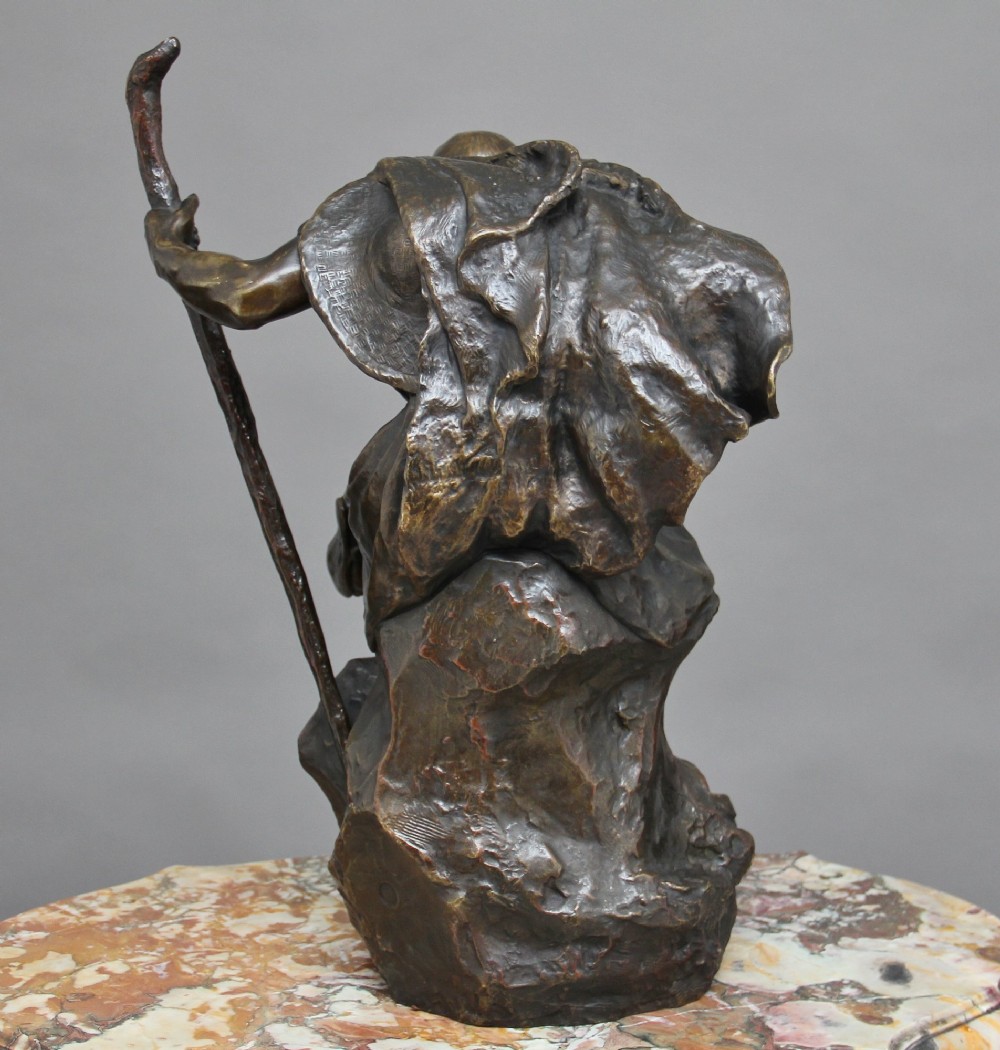 A 19th-century patinated bronze sculpture depicting the mythological figure Oedipus seated on a rock in contemplation while holding a staff. View VI