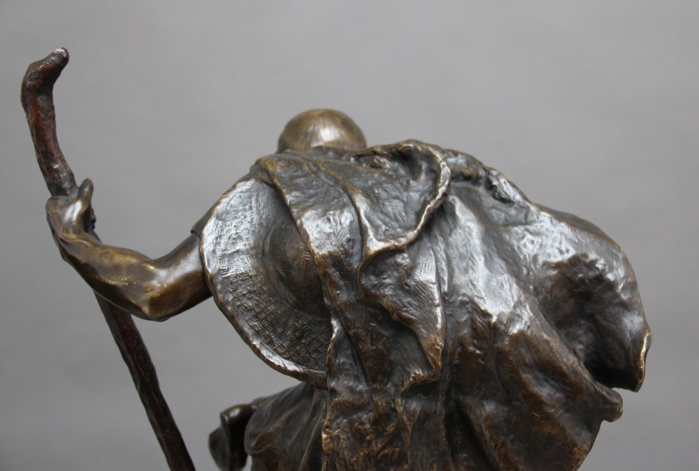 A 19th-century patinated bronze sculpture depicting the mythological figure Oedipus seated on a rock in contemplation while holding a staff. View XII